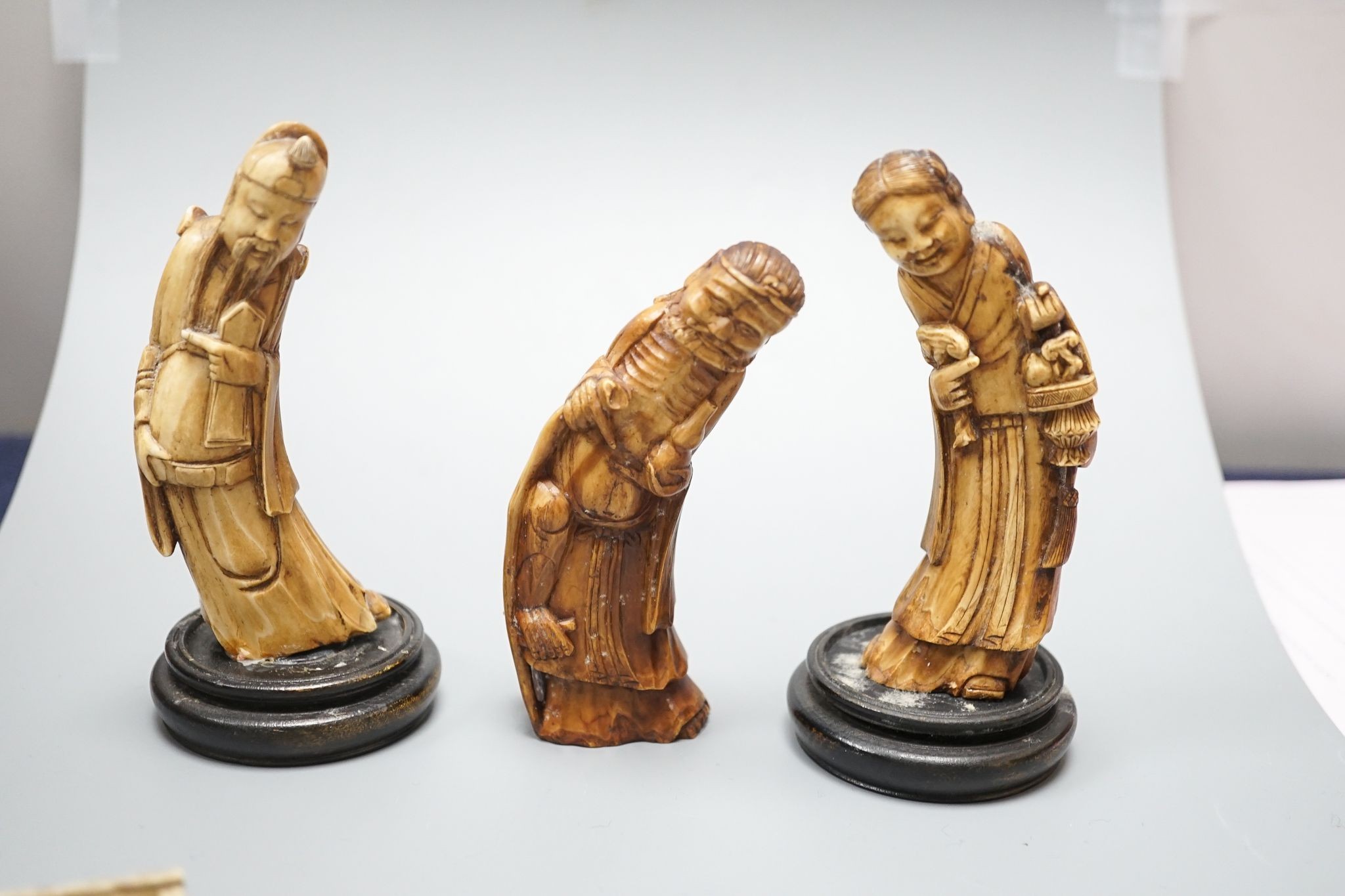 Three Chinese carved hippo tooth figures of Immortals, a 19th-century bone boxed dominoes set and a 19th-century ivory case set of dominoes